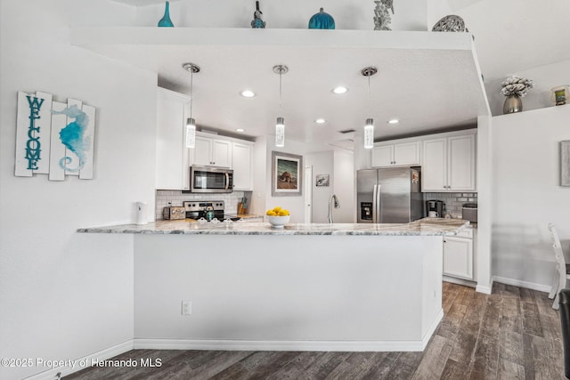 kitchen featuring decorative light fixtures, white cabinetry, kitchen peninsula, stainless steel appliances, and dark wood-type flooring