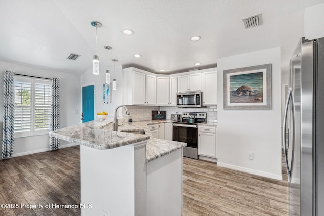 kitchen with sink, white cabinetry, hanging light fixtures, appliances with stainless steel finishes, and kitchen peninsula