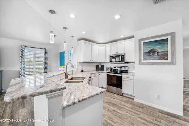 kitchen featuring pendant lighting, sink, appliances with stainless steel finishes, white cabinets, and kitchen peninsula