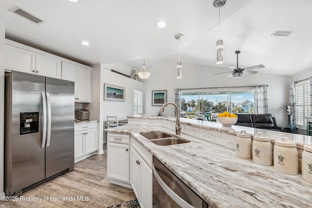 kitchen featuring stainless steel appliances, white cabinetry, hanging light fixtures, and sink