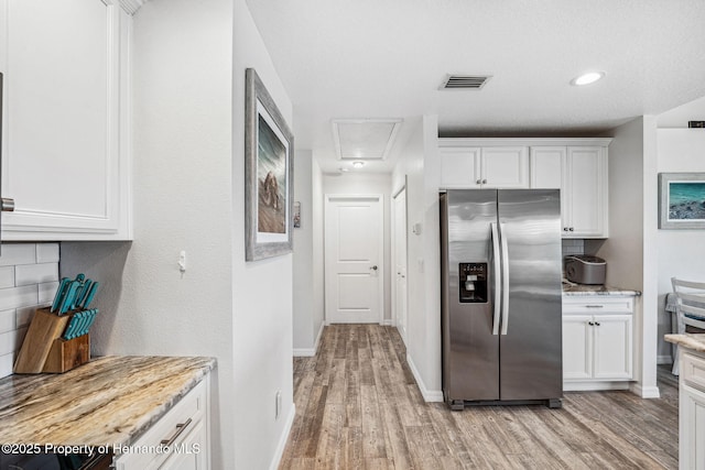 kitchen featuring white cabinetry, light stone counters, tasteful backsplash, light hardwood / wood-style floors, and stainless steel fridge with ice dispenser