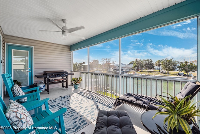 sunroom featuring a water view and ceiling fan