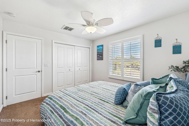 carpeted bedroom with ceiling fan, a closet, and a textured ceiling