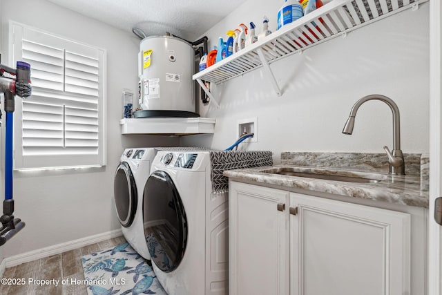 laundry room featuring sink, water heater, independent washer and dryer, cabinets, and light hardwood / wood-style floors