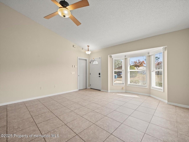 tiled empty room featuring ceiling fan and a textured ceiling