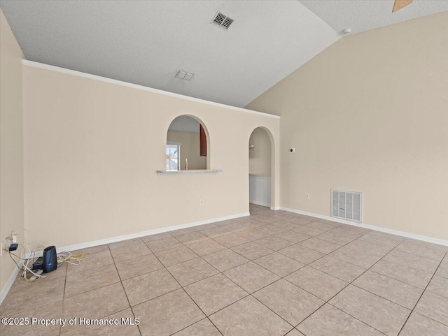 unfurnished room with a textured ceiling, light tile patterned floors, and lofted ceiling