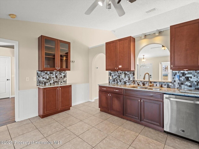 kitchen featuring stainless steel dishwasher, decorative backsplash, sink, vaulted ceiling, and light tile patterned floors