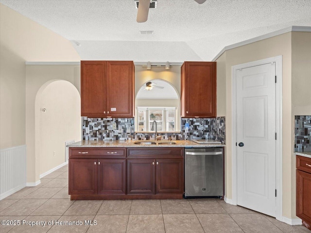 kitchen with ceiling fan, vaulted ceiling, stainless steel dishwasher, sink, and a textured ceiling