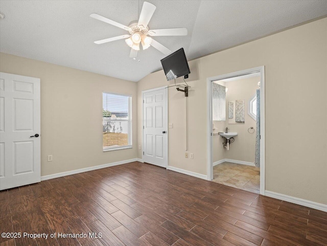 unfurnished bedroom with a textured ceiling, lofted ceiling, sink, ceiling fan, and ensuite bathroom