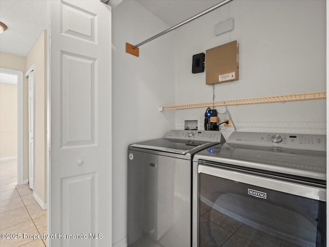 clothes washing area with a textured ceiling, washer and clothes dryer, and light tile patterned flooring