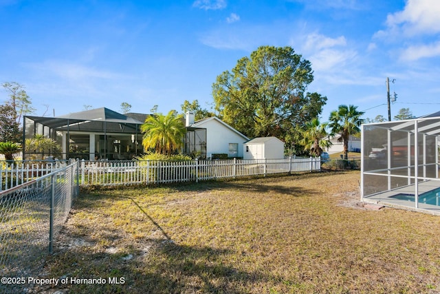 view of yard with a lanai, a fenced in pool, and a storage shed