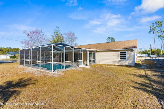 back of house with a lanai and a lawn