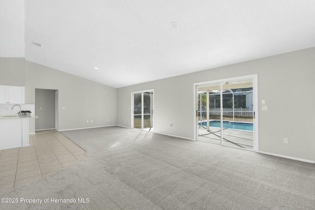 unfurnished living room featuring sink, lofted ceiling, and light carpet