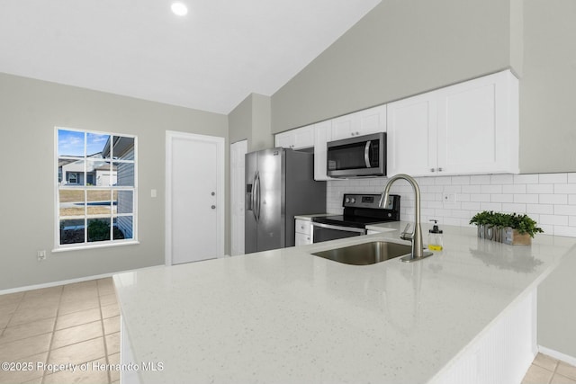 kitchen featuring lofted ceiling, tasteful backsplash, kitchen peninsula, appliances with stainless steel finishes, and white cabinets