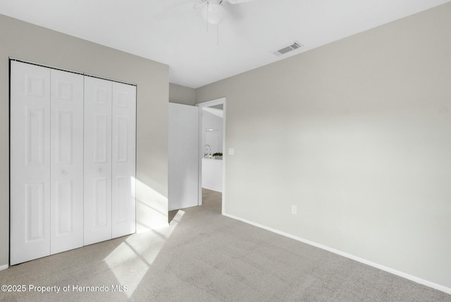 unfurnished bedroom featuring light carpet, a closet, and ceiling fan