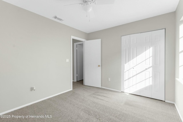 unfurnished bedroom featuring ceiling fan, a closet, and light carpet