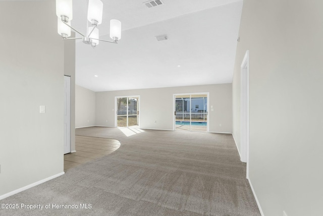 unfurnished living room featuring an inviting chandelier and light colored carpet