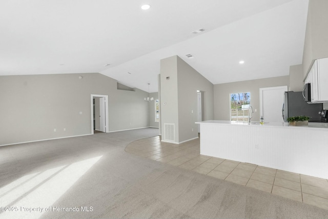 unfurnished living room with light colored carpet, sink, lofted ceiling, and an inviting chandelier