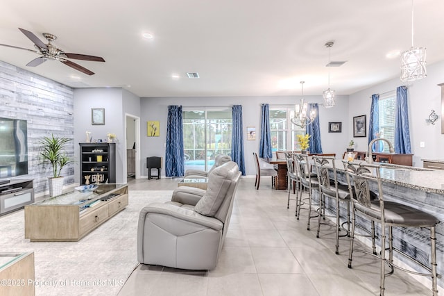 tiled living room featuring sink and ceiling fan with notable chandelier