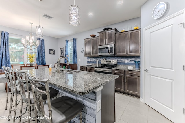 kitchen featuring hanging light fixtures, a kitchen bar, sink, and appliances with stainless steel finishes