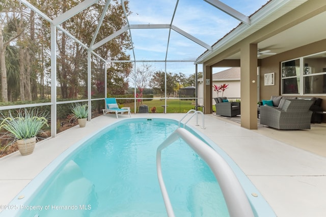 view of pool featuring an outdoor living space, ceiling fan, glass enclosure, and a patio area