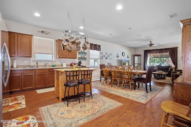 kitchen featuring a kitchen island, sink, stainless steel fridge, a kitchen breakfast bar, and dark hardwood / wood-style flooring