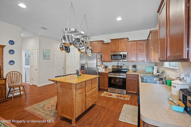 kitchen featuring dark hardwood / wood-style flooring, sink, stainless steel appliances, and a kitchen island