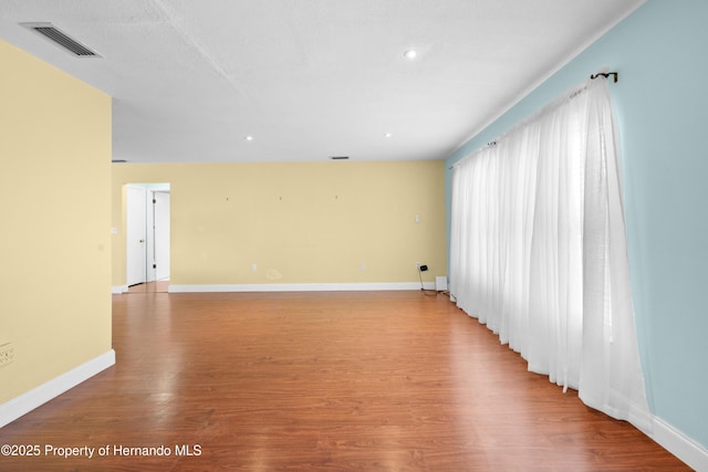 spare room with baseboards, visible vents, and wood finished floors