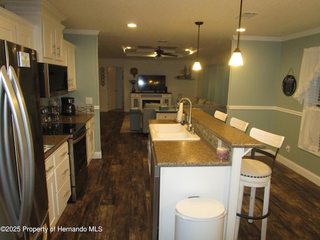 kitchen featuring appliances with stainless steel finishes, hanging light fixtures, a kitchen breakfast bar, sink, and an island with sink