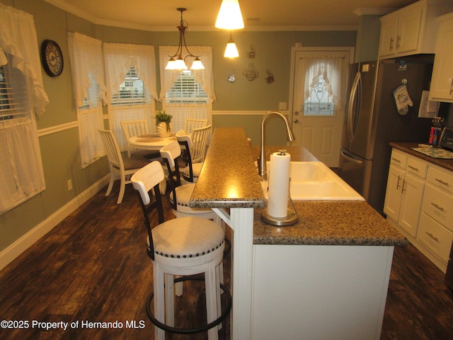 kitchen featuring white cabinetry, sink, pendant lighting, and a center island with sink