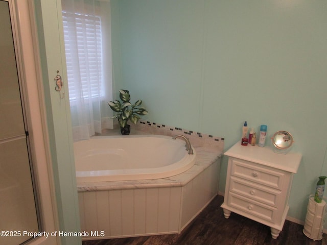 bathroom featuring wood-type flooring and tiled tub