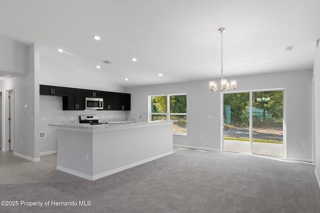 kitchen featuring light stone countertops, appliances with stainless steel finishes, decorative light fixtures, light colored carpet, and an inviting chandelier