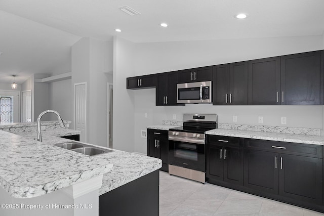 kitchen with sink, appliances with stainless steel finishes, a center island with sink, and vaulted ceiling