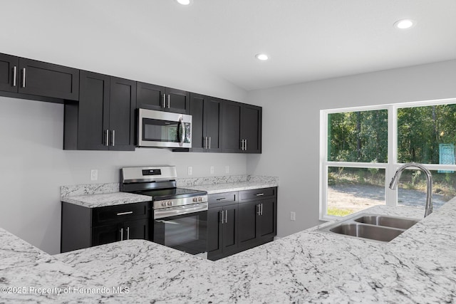 kitchen with light stone countertops, sink, lofted ceiling, and stainless steel appliances