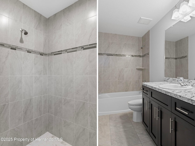 full bathroom featuring toilet, vanity, tiled shower / bath, and tile patterned flooring