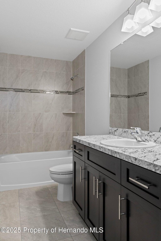 full bathroom featuring vanity, toilet, tiled shower / bath, and tile patterned floors