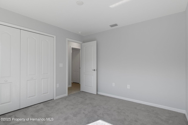 unfurnished bedroom featuring a closet and light carpet