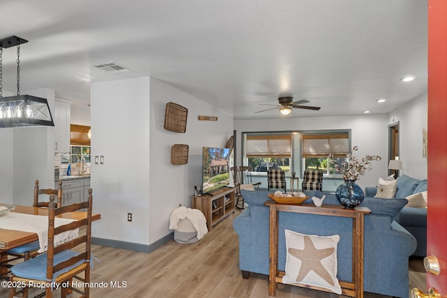 living room featuring ceiling fan, sink, and light wood-type flooring