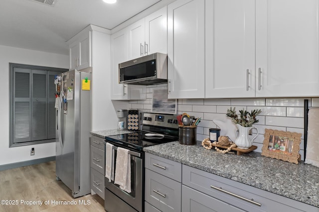 kitchen featuring white cabinetry, decorative backsplash, light hardwood / wood-style floors, stainless steel appliances, and light stone countertops