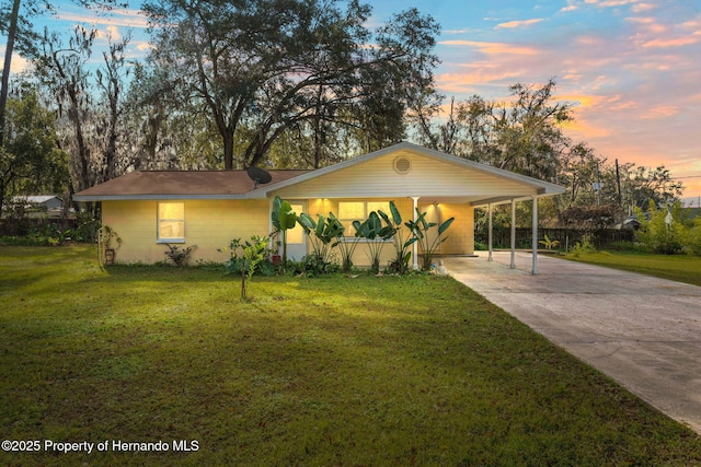 ranch-style home featuring a lawn and a carport