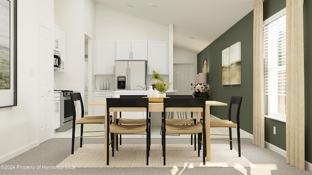 kitchen featuring white cabinetry, lofted ceiling, stainless steel appliances, and light carpet