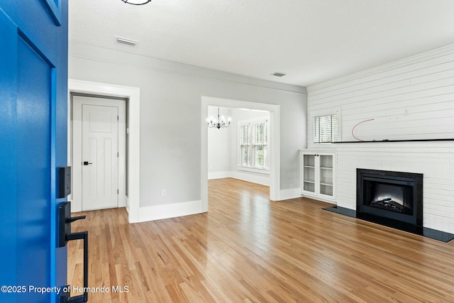 unfurnished living room with a fireplace, light hardwood / wood-style floors, and a textured ceiling