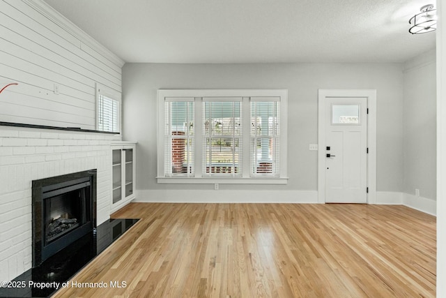 unfurnished living room with hardwood / wood-style flooring, a fireplace, and a textured ceiling