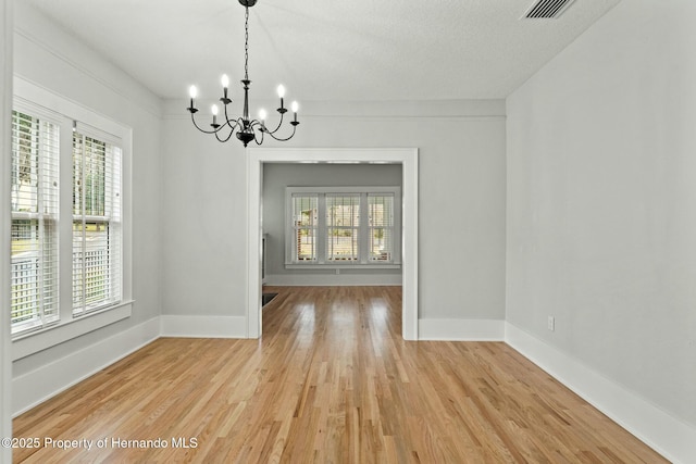 unfurnished dining area featuring light hardwood / wood-style flooring and a chandelier