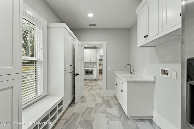 laundry room featuring cabinets, hookup for a washing machine, sink, and a wealth of natural light