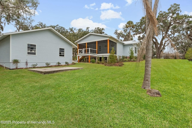 rear view of property with a patio area, a sunroom, and a lawn