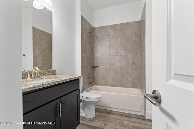 full bathroom featuring tiled shower / bath combo, vanity, wood-type flooring, and toilet