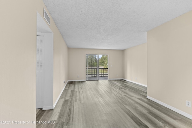 spare room featuring hardwood / wood-style floors and a textured ceiling