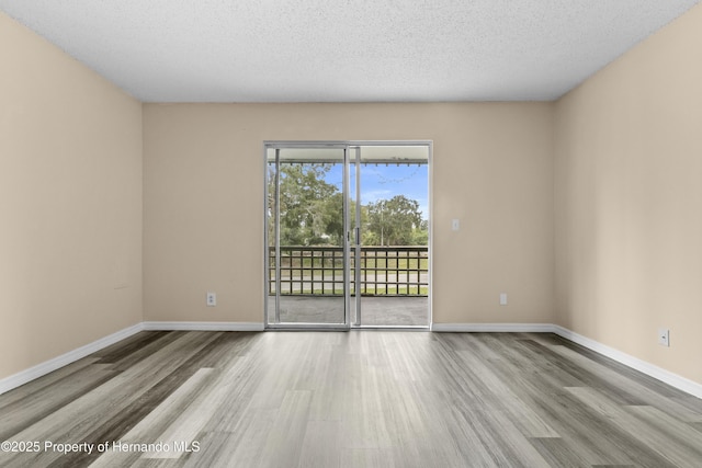 empty room with light hardwood / wood-style flooring and a textured ceiling