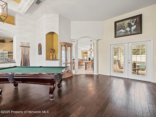 recreation room featuring decorative columns, a towering ceiling, and french doors